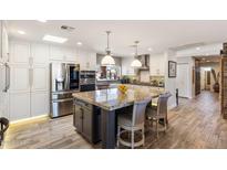 Gourmet kitchen with stainless steel appliances, white cabinets, stone countertops, and an island with seating at 7510 E Larkspur Dr, Scottsdale, AZ 85260