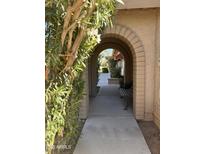 Inviting arched walkway with brick accents leads to a charming bench and landscaped entryway at 10102 E Michigan Ave, Sun Lakes, AZ 85248