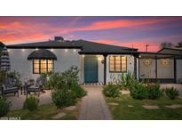 Charming single-story home featuring a vibrant front door, lush landscaping, and a cozy outdoor seating area at 2041 N 16Th Ave, Phoenix, AZ 85007