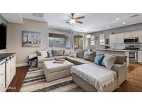 Bright living room features a large sectional sofa, wood flooring, and sliding glass doors to backyard at 12118 W Dove Wing Way, Peoria, AZ 85383