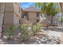 Multi-level condo building with beige stucco exterior, landscaping, and stairways to upper units at 15050 N Thompson Peak Pkwy # 1001, Scottsdale, AZ 85260