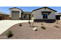 Charming single-story home features a neutral exterior with stone accents, a two-car garage, and low-maintenance landscaping at 17324 W Royal Palm Rd, Waddell, AZ 85355