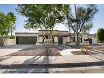 Charming home exterior with a dark garage door, desert landscaping, and a welcoming entrance under a bright, sunny sky at 1736 N Ashbrook Cir, Mesa, AZ 85213