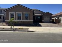 Charming single-story home featuring stone accents and a well-manicured front yard and a brick driveway at 21845 E Bonanza Ct, Queen Creek, AZ 85142