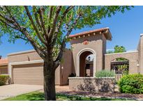 Inviting beige home featuring an arched entrance, red tile roof, and mature landscaping with trees at 25230 S Berry Brook Dr, Sun Lakes, AZ 85248