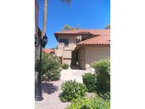 Charming two-story home featuring a red tile roof, an attached garage, and lush landscaping with vibrant flowering bushes at 8700 E Mountain View Rd # 2029, Scottsdale, AZ 85258