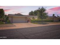 Charming single-story home with a well-manicured front yard and attached two-car garage, set against a beautiful sunrise at 12927 W Shadow Hills Dr, Sun City West, AZ 85375
