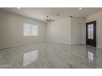 Spacious living room with high ceilings, modern ceiling fan, and stylish tile flooring at 13430 S Garnet Rd, Buckeye, AZ 85326