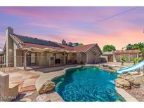 Backyard pool with a slide and stone features is surrounded by a fence and has a covered patio area for relaxing at 15825 N 45Th St, Phoenix, AZ 85032