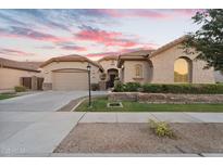 Charming home featuring a two-car garage, complemented by lush landscaping and a serene sunset backdrop at 2103 E Canyon Pl, Chandler, AZ 85249