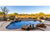 Beautiful backyard pool with rock waterfall feature and desert views in a private setting at 40619 N Candlewyck Ln, Phoenix, AZ 85086