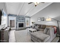 Bright living room with vaulted ceilings, modern decor, a decorative fireplace, and a comfortable sectional sofa at 4502 W Continental Dr, Glendale, AZ 85308