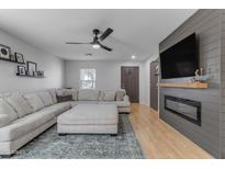 Open living room with a large sectional sofa, modern ceiling fan and electric fireplace at 48069 N Rico Way, Gold Canyon, AZ 85118