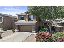 Inviting two-story home with stone accents, a two-car garage, mature landscaping, and a blooming pink bush at 1162 E Ranch Ct, Gilbert, AZ 85296