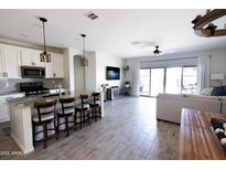 Open concept living room featuring a kitchen island with granite countertops and stainless appliances at 1364 W Spine Tree Ave, Queen Creek, AZ 85140