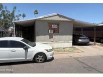 Modest single-story home featuring a covered carport and mature trees in a desert landscape at 2060 N Center St # 282, Mesa, AZ 85201
