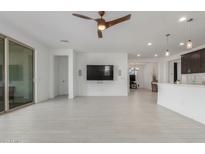 Spacious living room featuring white tile flooring, a modern ceiling fan, and a wall-mounted television for entertainment at 25601 N 140Th Ln, Surprise, AZ 85387