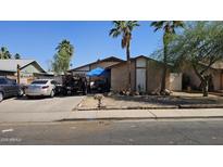 Modest single-story home with mature trees, a covered carport, and off-street parking in front of the house at 604 W Emelita Ave, Mesa, AZ 85210