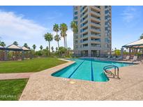Community pool with palm trees and lounge chairs in front of a high-rise condominium building on a sunny day at 1040 E Osborn Rd # 501, Phoenix, AZ 85014