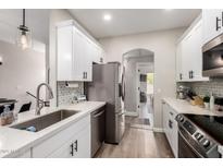 Modern kitchen features white cabinetry, stainless steel appliances, and stylish backsplash at 1411 E Orangewood Ave # 233, Phoenix, AZ 85020