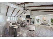 Bright living room boasts wood beam ceiling, brick fireplace, and open layout to dining area and kitchen at 2178 E Golf Ave, Tempe, AZ 85282