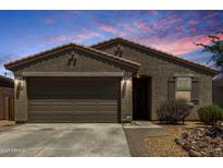 Charming single-story home featuring a two-car garage, desert landscaping, and a tiled roof against a vibrant sky at 40380 W Jenna Ln, Maricopa, AZ 85138