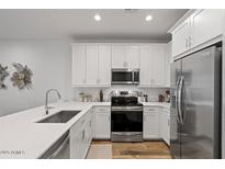 Modern kitchen featuring stainless steel appliances, white cabinets, and wood flooring at 4157 E Pinto Dr, Gilbert, AZ 85296