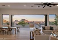 Open living room with a view to the outside through expansive glass doors; dining set to the left and sofa to the right at 13631 E Windrose Dr, Scottsdale, AZ 85259