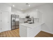 Bright white kitchen with stainless steel appliances, quartz countertops, island, and wood-look flooring at 7601 E Roosevelt St # 1012, Scottsdale, AZ 85257