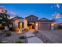 Charming single-story home showcasing a stone facade, manicured landscape, and a welcoming brick pathway at 18544 W Devonshire Ave, Goodyear, AZ 85395