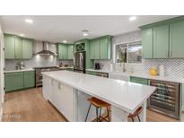 Bright kitchen features custom green cabinets, stainless appliances, a white backsplash, and an oversized center island at 2402 E Cinnabar Ave, Phoenix, AZ 85028