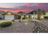 Charming home featuring desert landscaping, a chimney, and a two-car garage against a stunning pink sky at dusk at 2422 W Acoma Dr, Phoenix, AZ 85023