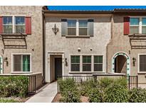 Charming townhome featuring a neutral stucco facade, colorful shutters, and lush landscaping at 2631 S Sulley Dr # 104, Gilbert, AZ 85295