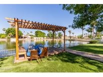 Scenic view of the community lake with a wooden pergola, charming boats, and serene water reflecting the clear sky at 3109 N Meadow Dr, Avondale, AZ 85392