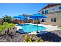 Inviting backyard pool area with blue umbrellas, lush greenery, and a beautiful sunny sky at 3247 E Creosote Ln, Gilbert, AZ 85298