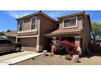 Two-story stucco home with a tile roof, desert landscaping, and a splash of color from blooming bougainvillea at 43822 W Baker Dr, Maricopa, AZ 85138
