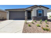 Charming single-story home featuring a stone facade, neutral color palette, and well-manicured desert landscaping at 8577 W Trenton Ct, Florence, AZ 85132