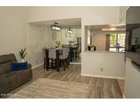 Cozy living room features modern wood flooring, a comfortable couch, and an adjacent dining area with bar stool seating at 9450 N 94Th Pl # 205, Scottsdale, AZ 85258