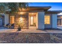 Charming home featuring a stone facade and a well-lit entrance with a lovely garden at 13186 W Via Dona Rd, Peoria, AZ 85383
