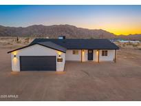 Beautiful single-story home with a dark gray garage door and mountain views at 16630 N Slate Ln, Maricopa, AZ 85139