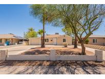 Charming single-story home featuring a well-manicured desert landscape and mature trees at 1811 W Roma Ave, Phoenix, AZ 85015