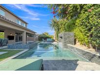 Backyard pool area with a water feature, seating area, and beautiful landscaping at 2219 E Galileo Dr, Gilbert, AZ 85298