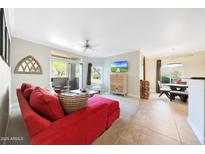 Bright living room with a red sofa, ceiling fan, sliding doors to a patio, and an entertainment area at 5335 E Shea Blvd # 1087, Scottsdale, AZ 85254