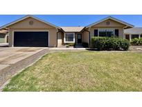 Charming single-story home with a manicured lawn, black garage door, and inviting front entrance at 6419 W Monte Cristo Ave, Glendale, AZ 85306