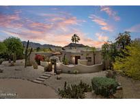 Stunning Santa Fe home showcasing desert landscaping, an elegant courtyard and a striking mountain backdrop at sunset at 9349 E Calle De Valle Dr, Scottsdale, AZ 85255