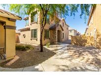 Two-story home featuring a stone-accented entrance and neutral stucco, complemented by desert landscaping at 935 E Agua Fria Ln, Avondale, AZ 85323