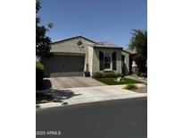 Charming single story home with a well-manicured lawn, a grey garage door, and desert landscaping at 10704 E Twister Ave, Mesa, AZ 85212
