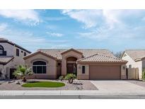 Tan home featuring a tile roof, well-maintained landscaping, and a two-car garage at 1398 W Windhaven Ave, Gilbert, AZ 85233