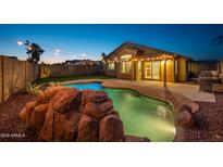 Backyard with a beautiful rock-feature pool, string lights, and a covered patio for relaxing evenings at 6309 W Hughes Dr, Phoenix, AZ 85043