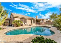 Backyard pool featuring travertine tile surround, covered patio, and secure fencing for safety at 6713 E Paradise Ln, Scottsdale, AZ 85254